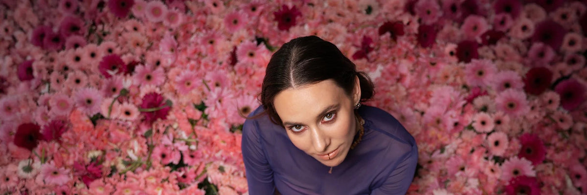 Malou Lovis sitzt auf einem Teppich aus pinken Blumen